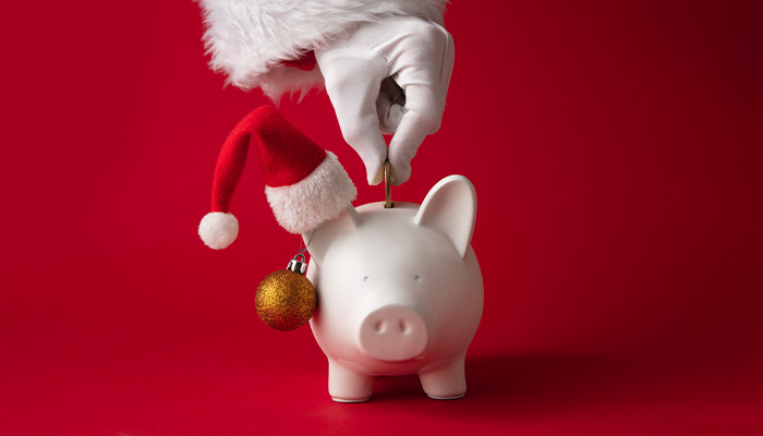 Una persona introduce una moneda en un cerdo en representación de ahorro