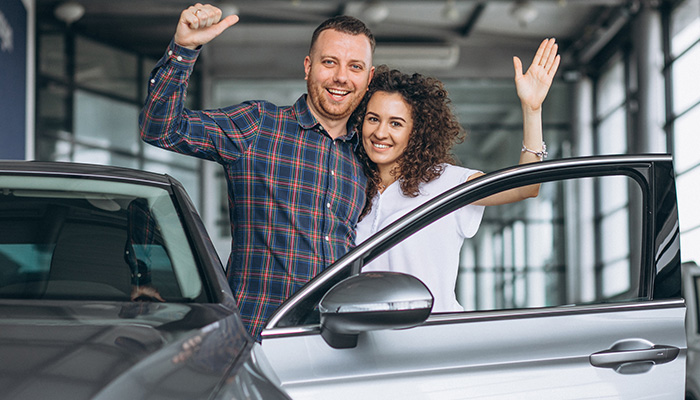 Un hombre y una mujer saludan desde un coche